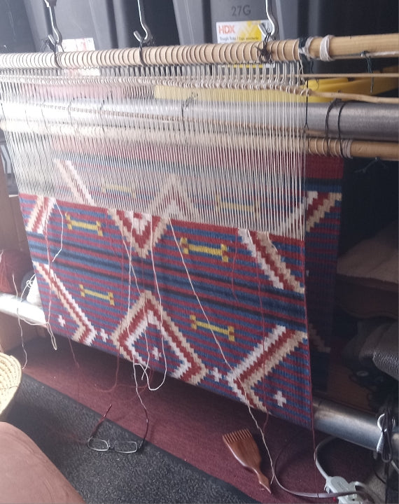 Manta Weaving loom with a partially completed multicolored pattern