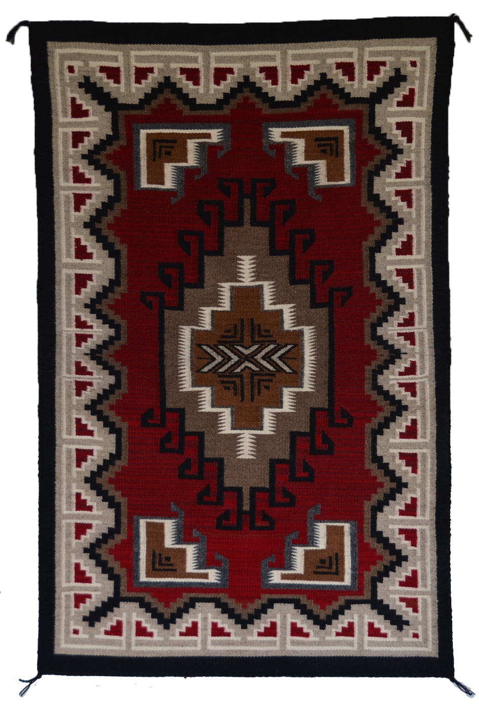 A Teec Nos Pos rug with a Southwestern geometric pattern, featuring a deep red center, beige and brown medallions, and a black and beige border.
