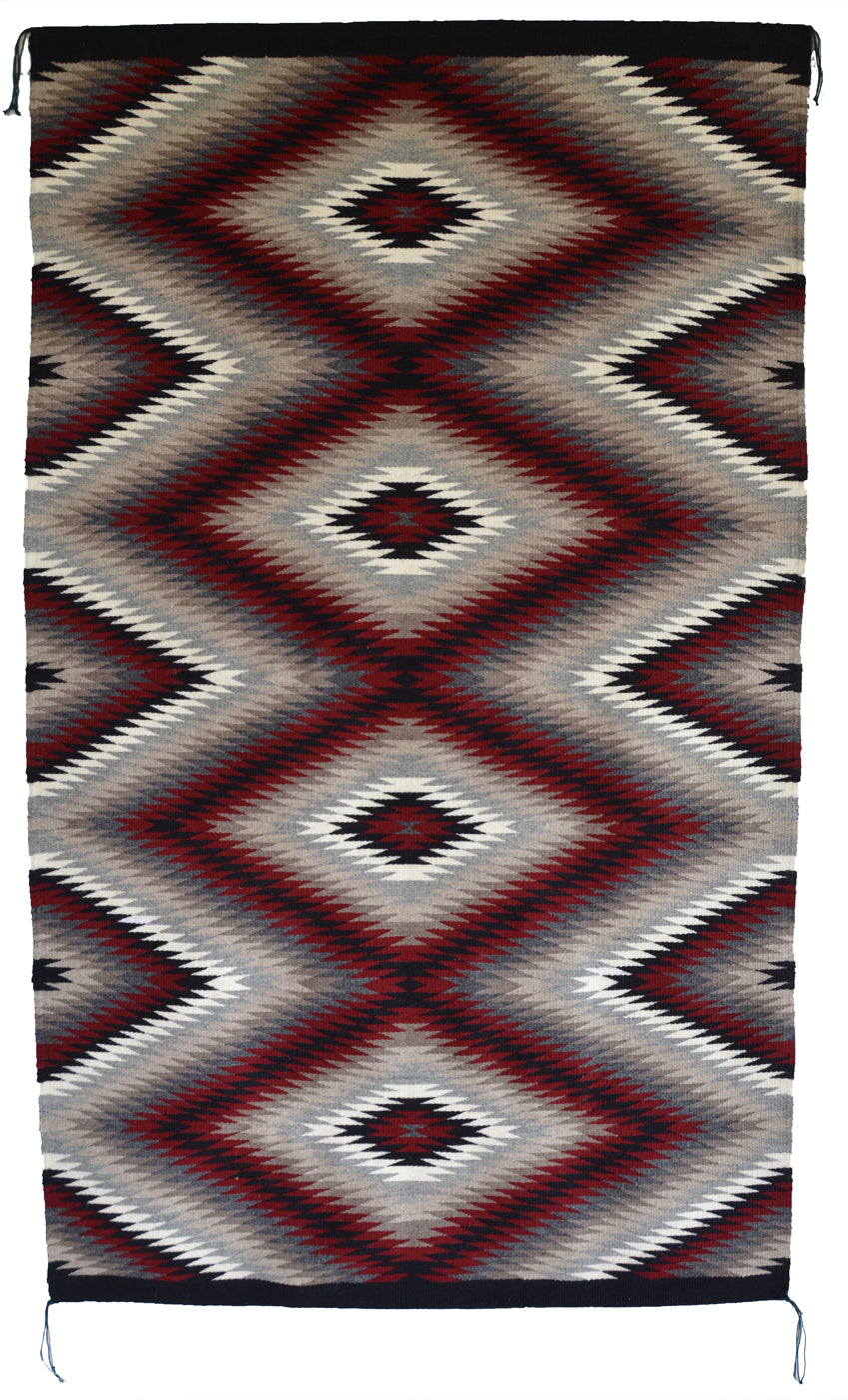 A Navajo eye dazzler rug with a Southwestern geometric diamond pattern in dark red, black, gray, beige, and white, shown flat against a white background.