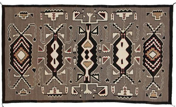 A Teec Nos Pos rectangular Navajo rug featuring Hero Twin designs, predominantly in brown tones with white and darker accents.