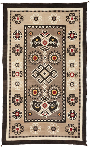 A vintage Bistie Navajo rug with geometric curvilinear designs, predominantly in brown, beige, and red, with a visible eagle tail design.