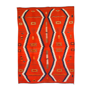 A traditional Navajo weaving featuring a red background with geometric patterns in blue, beige, and black.
